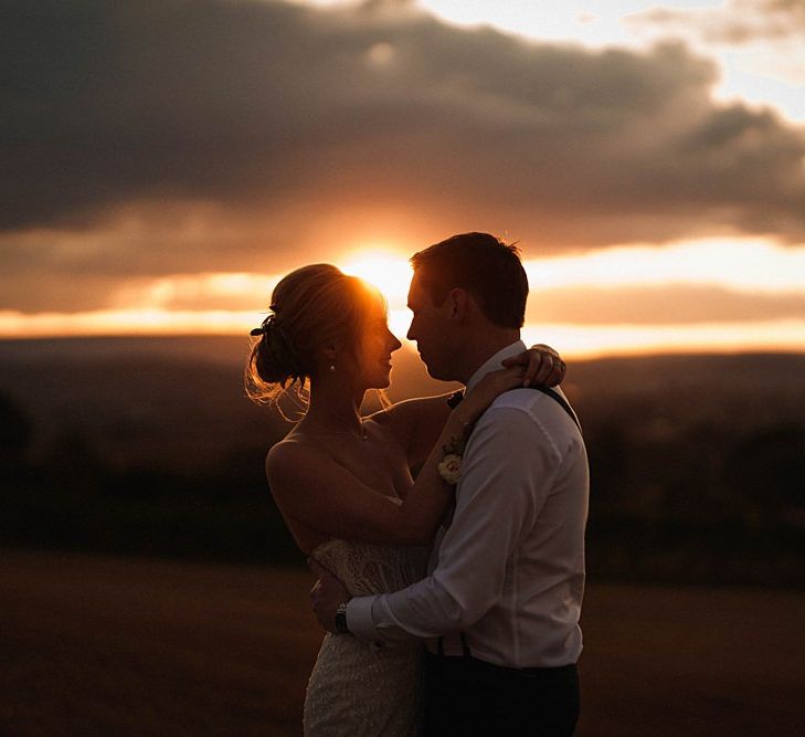 Bride and groom embrace for sunset shot at outdoor autumn day