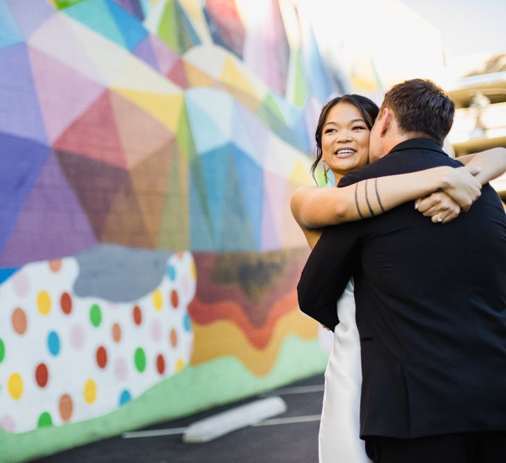 Bride in Silk BHLDN Dress with Spaghetti Straps and V-Back | Groom in Black Tuxedo with Emerald Green Bow Tie | Bridal Ponytail | First Look Photo | Las Vegas Wedding with Gold Sequin Bridesmaids Dresses and Silk Flowers | Chris Barber Photography