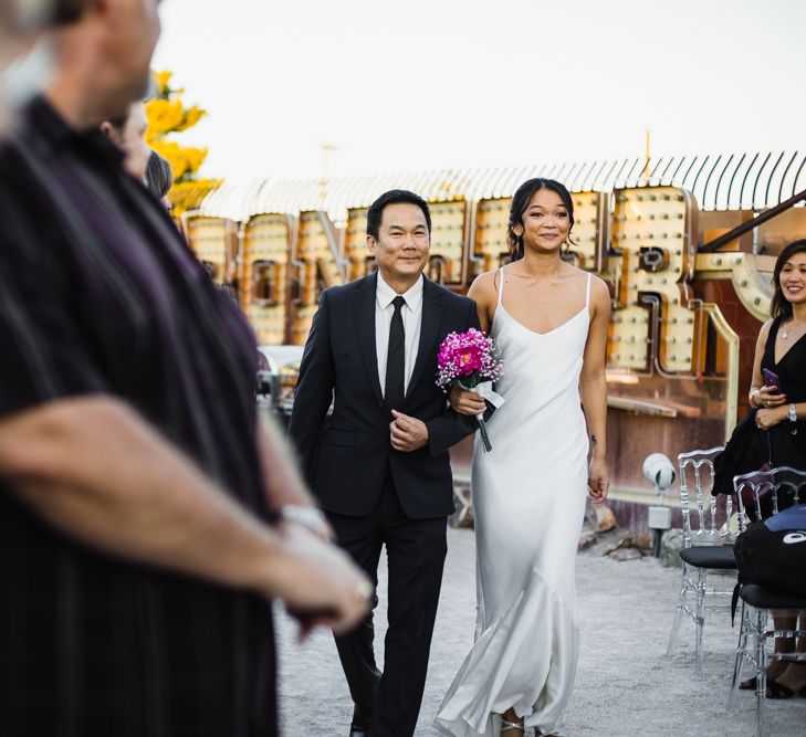 Bride in Silk BHLDN Dress with Spaghetti Straps and V-Back | Bridal Ponytail | Fuschia Sweet Pea Spray Silk Flowers Bouquet | Entrance of the Bride | Father of the Bride in Black Suit | Las Vegas Wedding with Gold Sequin Bridesmaids Dresses and Silk Flowers | Chris Barber Photography