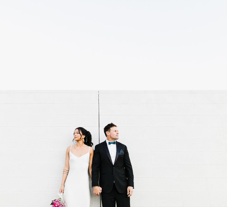 Bride in Silk BHLDN Dress with Spaghetti Straps and V-Back | Groom in Black Tuxedo with Emerald Green Bow Tie | Fuschia Sweet Pea Spray Silk Flowers Bouquet | Bridal Ponytail | Las Vegas Wedding with Gold Sequin Bridesmaids Dresses and Silk Flowers | Chris Barber Photography