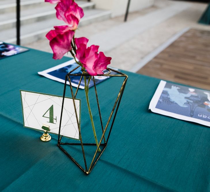 Gold Geometric Vase with Single Stem Silk Flower | Gold Table Number with Geometric Detail | Emerald Green Table Cloth | Custom Book Wedding Favours | Wedding Reception Table Décor at The Neon Museum | Las Vegas Wedding with Gold Sequin Bridesmaids Dresses and Silk Flowers | Chris Barber Photography