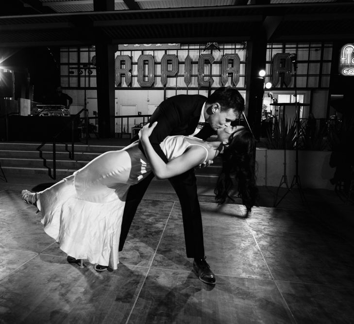 Bride in Silk BHLDN Dress with Spaghetti Straps and V-Back | Groom in Black Tuxedo with Emerald Green Bow Tie | Bridal Ponytail | First Dance | The Neon Museum | Las Vegas Wedding with Gold Sequin Bridesmaids Dresses and Silk Flowers | Chris Barber Photography