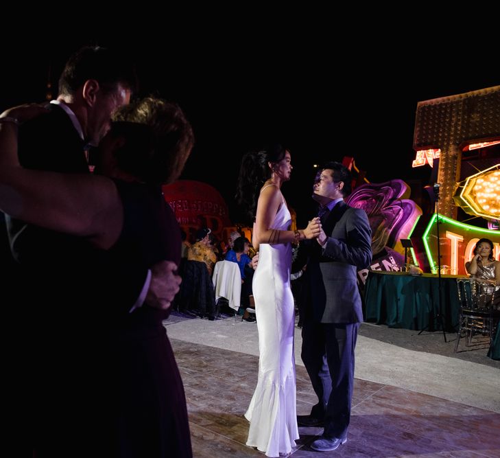 Bride in Silk BHLDN Dress with Spaghetti Straps and V-Back | Groom in Black Tuxedo with Emerald Green Bow Tie | Father Daughter Dance | Mother Son Dance | The Neon Museum | Las Vegas Wedding with Gold Sequin Bridesmaids Dresses and Silk Flowers | Chris Barber Photography