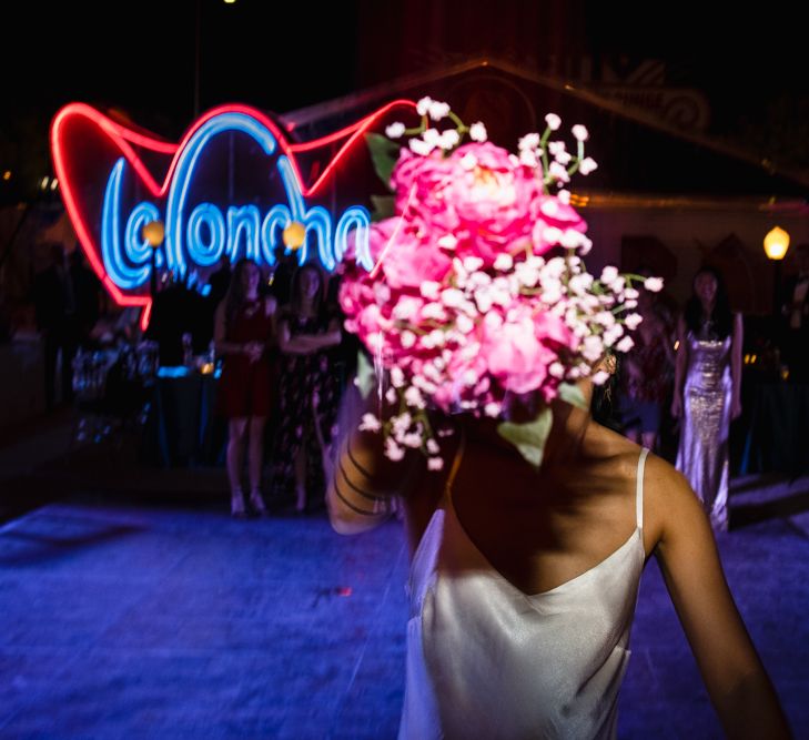 Fuschia Sweet Pea Spray Silk Flowers Bouquet | Bride in Silk BHLDN Dress with Spaghetti Straps and V-Back | Bouquet Toss | The Neon Museum | Las Vegas Wedding with Gold Sequin Bridesmaids Dresses and Silk Flowers | Chris Barber Photography