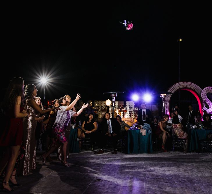 Bride in Silk BHLDN Dress with Spaghetti Straps and V-Back | Bridal Ponytail | Bouquet Toss | The Neon Museum | Las Vegas Wedding with Gold Sequin Bridesmaids Dresses and Silk Flowers | Chris Barber Photography