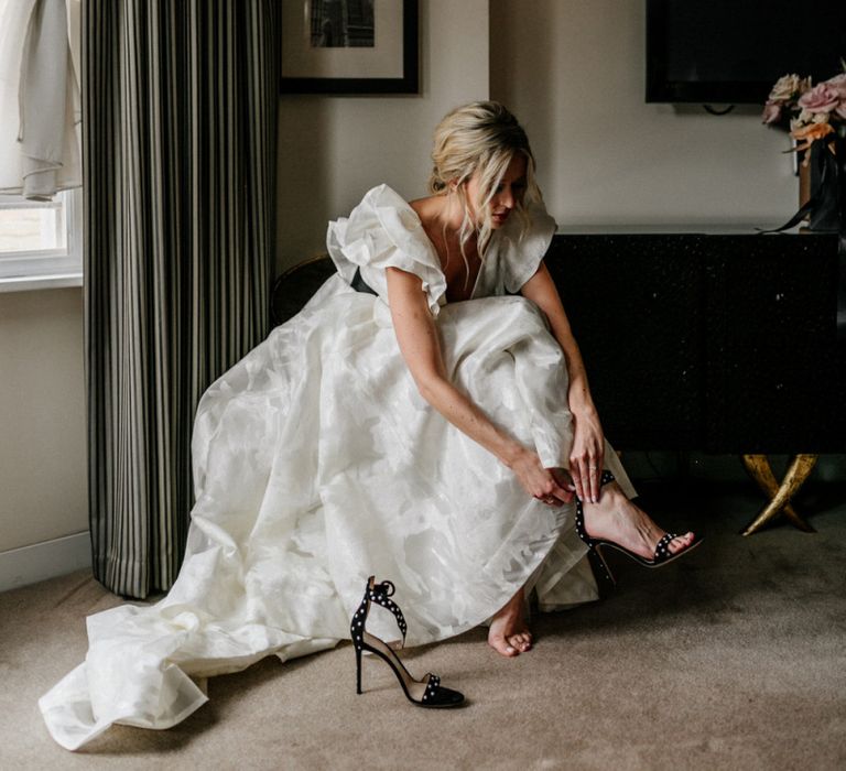 Bride Putting on Black Ankle Strap Sandals in Jesus Peiro Wedding Dress