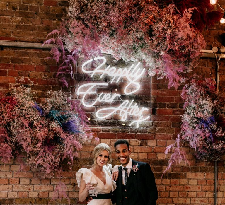 Bride and Groom Standing Under a Happily Ever After Neon Sign