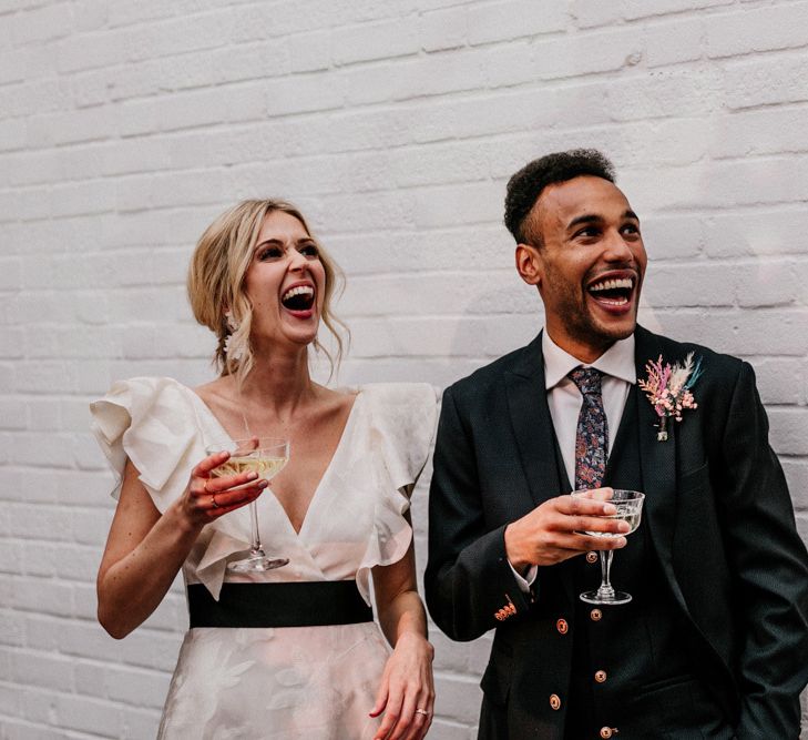 Bride in Jesus Peiro Wedding Dress with Ruffle Sleeves and Groom Laughing During Speeches