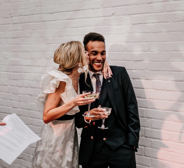 Bride in Ruffle Wedding Dress Kissing Her Groom During the Wedding Speeches