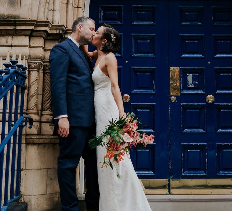 Bride Kisses Groom Holding Orange Wedding Flowers