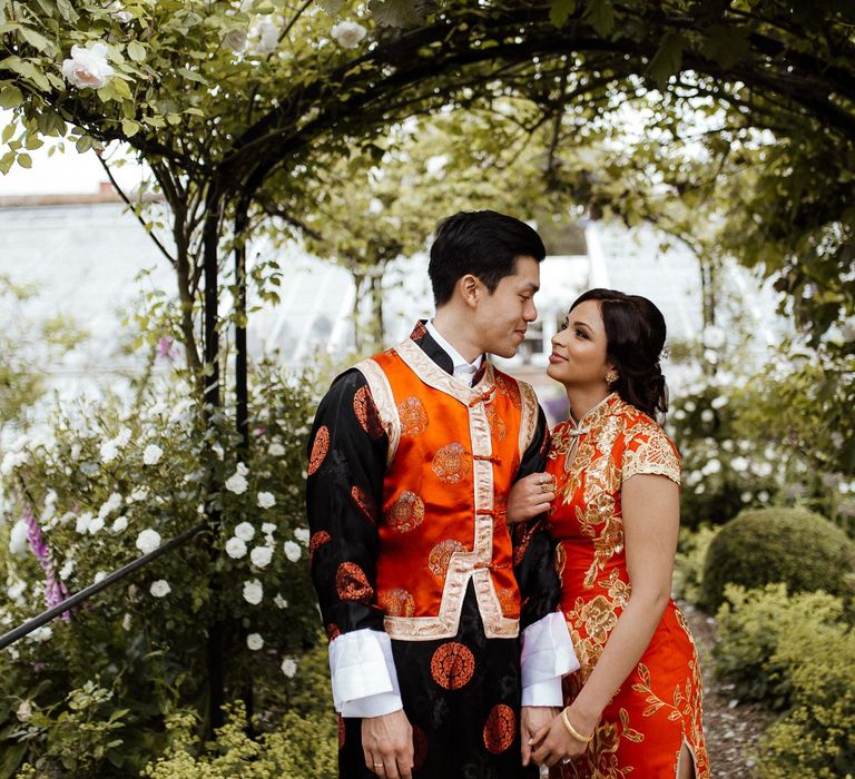 Bride and groom in traditional outfits for Chinese tea ceremony at fusion wedding