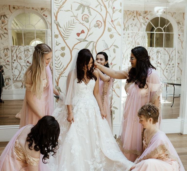 Bride in strapless wedding dress with bridal party in pink saris