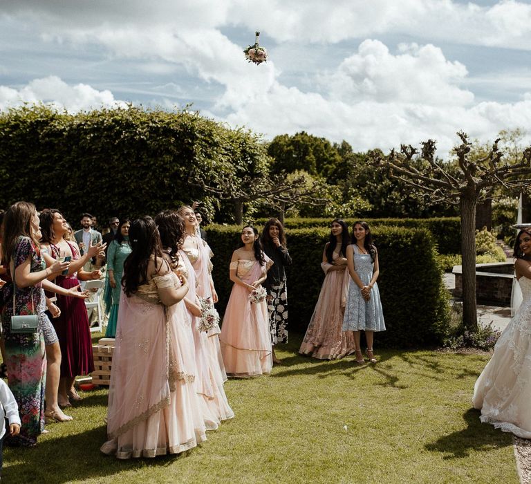 Bride throws bouquet to bridal party in sari dresses