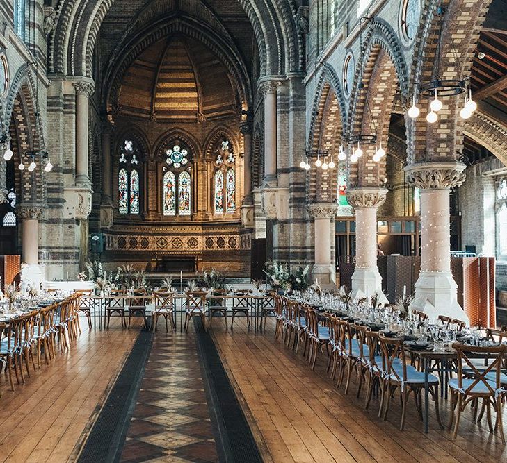 Long tables styled with dark and earthy tones mixed with metallic touches at St Stephens Trust wedding reception with balloon installation