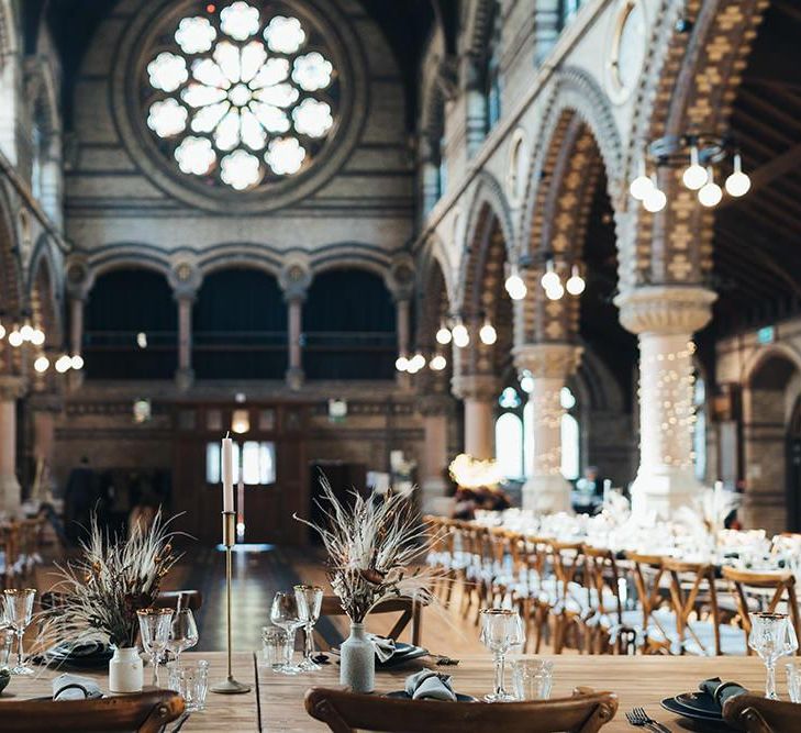 Long tables styled with dark and earthy tones mixed with metallic touches at St Stephens Trust wedding reception with balloon installation  and dried foliage decor