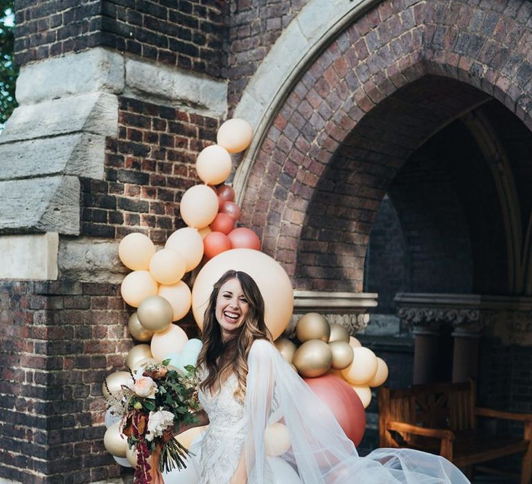 Bride wearing embellished custom made dress with watteau train and balloon installation