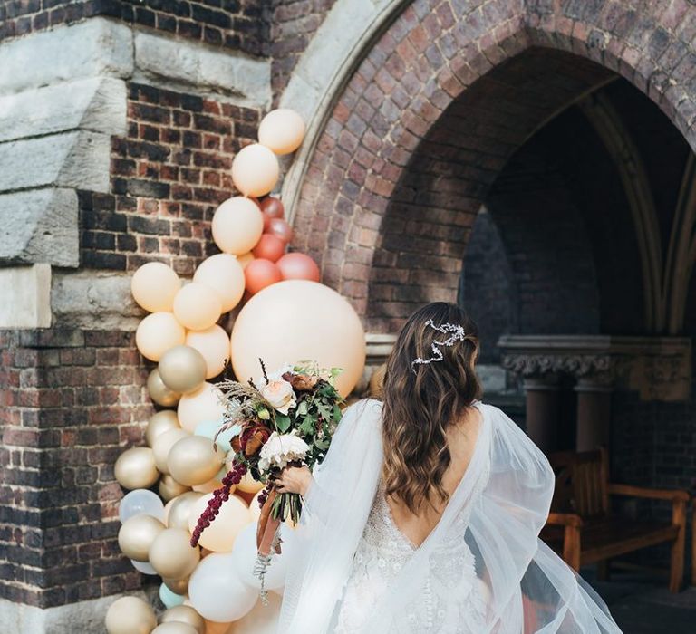 Back of brides beautifully embellished Emma Beaumont dress with beaded hair accessory and balloon installation