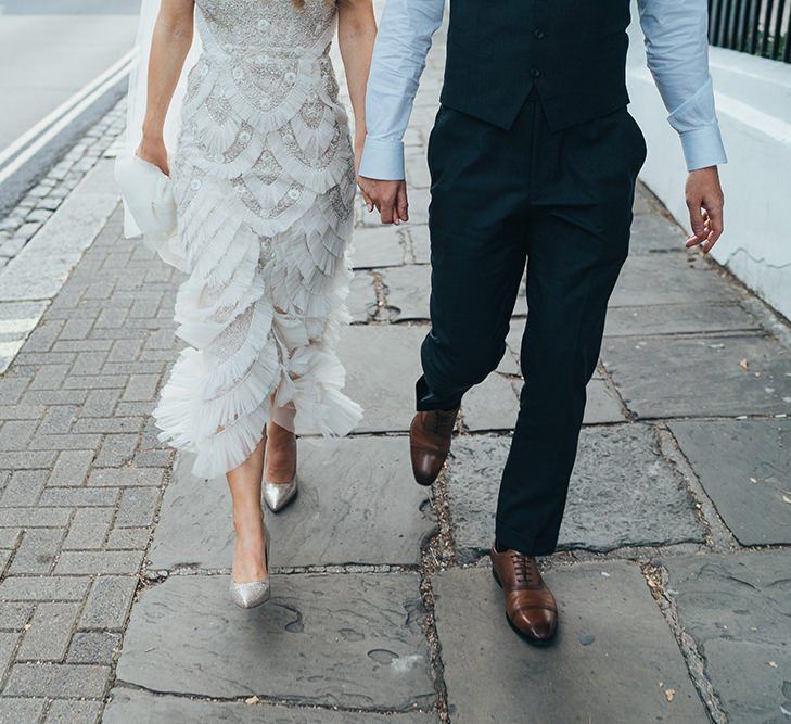 Bride wearing glitter stiletto shoes and embellished dress with the groom stealing a moment