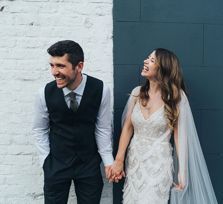 Groom in waistcoat and bride wearing custom made Emma Beaumont dress with detachable train