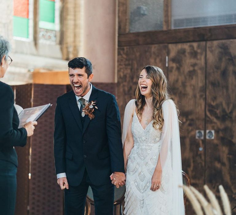 Bride and groom tie the knot at church ceremony wearing custom made embellished dress and groom with dried flower buttonhole arrangement