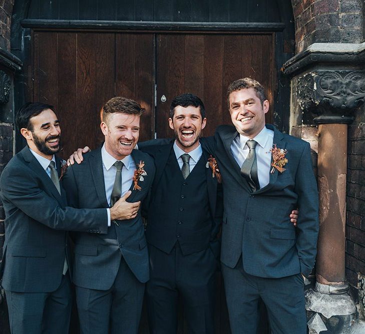 Groom and his groomsmen at church ceremony wearing dried floral button hole arrangements