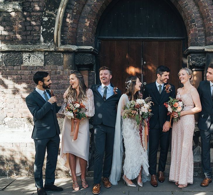 Bride and groom with their guests at church ceremony with balloon installation and peach wedding theme