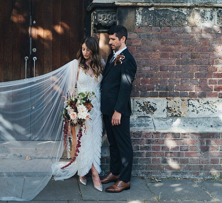 Brides beautifully embellished bridal dress and long watteau train at church ceremony with balloon installation and relaxed styling