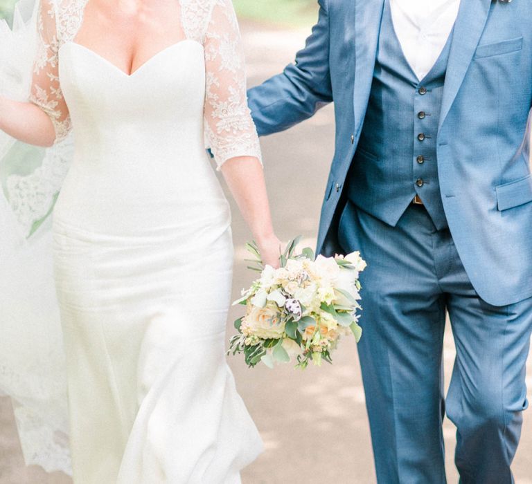 Stylish Bride in Suzanne Neville Wedding Dress and Lace Bolero and Groom in Navy Hugo Boss Suit  Walking Down a Country Lane