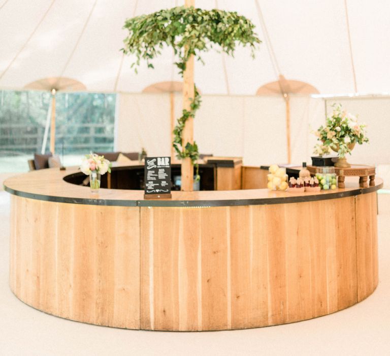 Wooden Bar with Foliage Chandelier in a Sperry Tent Reception