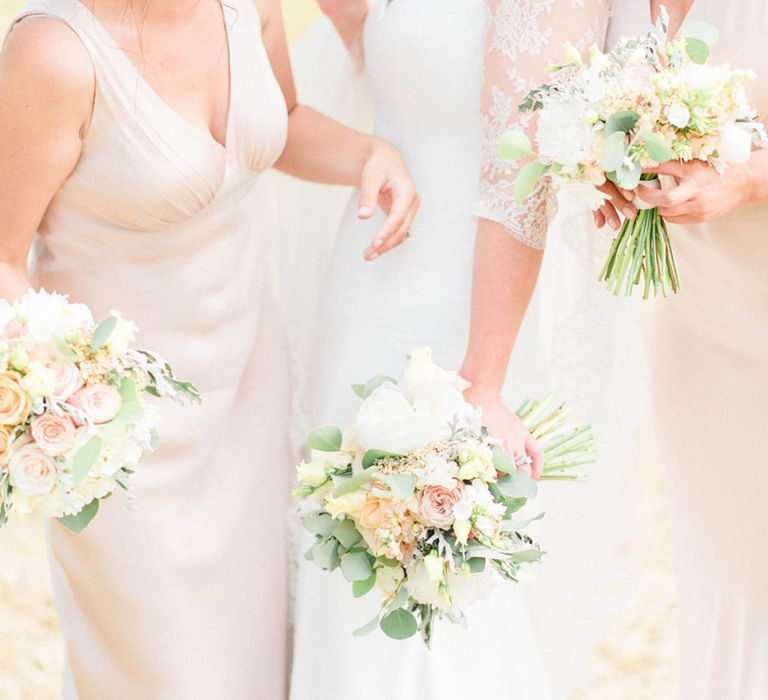 Bridesmaids in Oyster Ghost Dresses and Bride in Suzanne neville Wedding Dress and Lace Bolero Holding Pastel Peach Bouquets