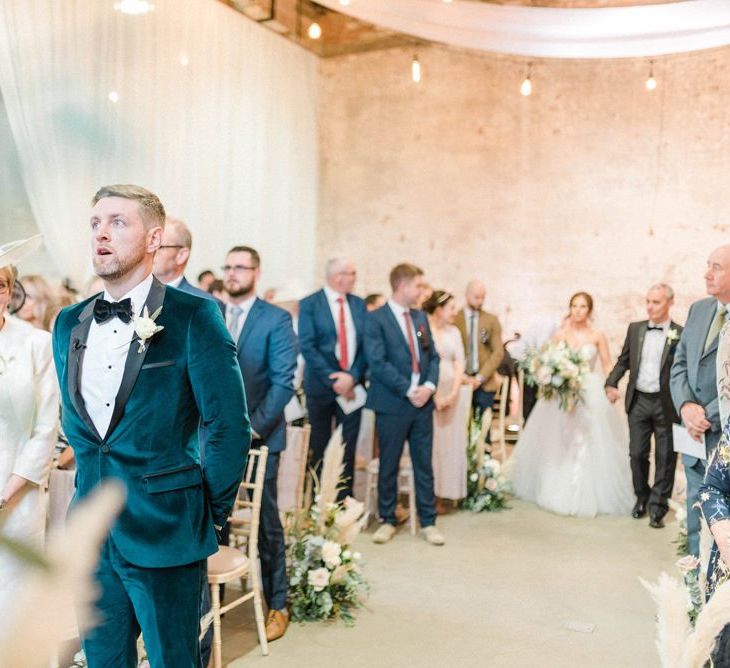 Groom in blue velvet jacket waits for bride in detachable skirt wedding dress