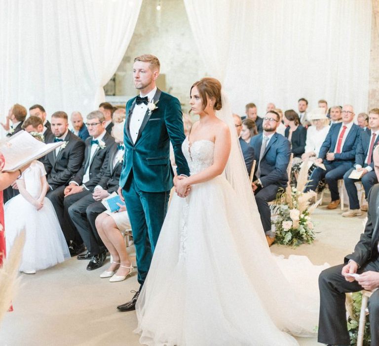 Bride in detachable skirt wedding dress with groom during ceremony at Calke Abbey