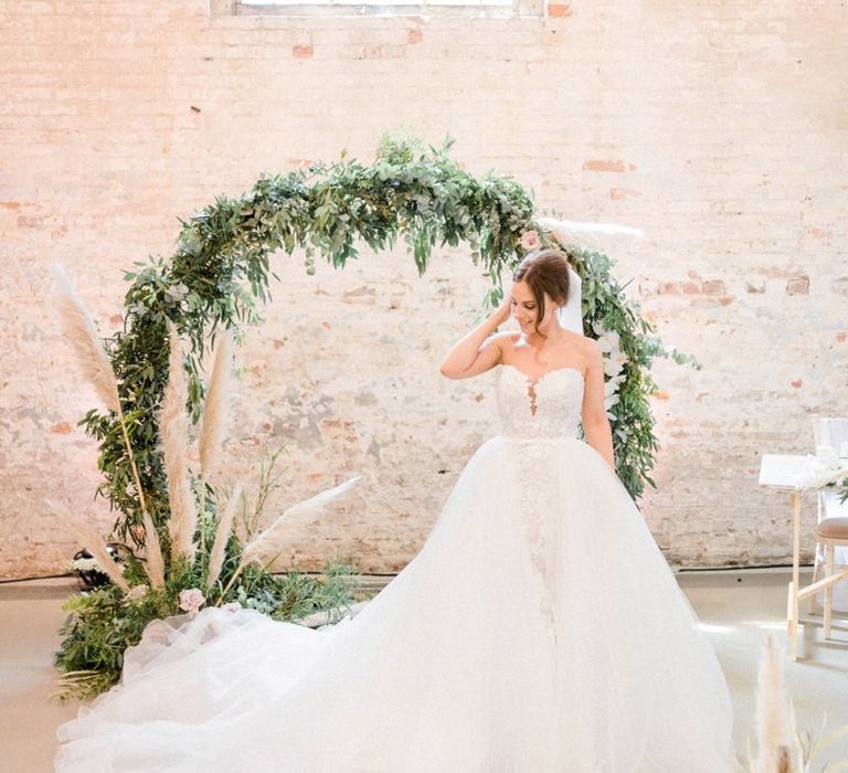 Bride in detachable skirt wedding dress in front of moon gate decor