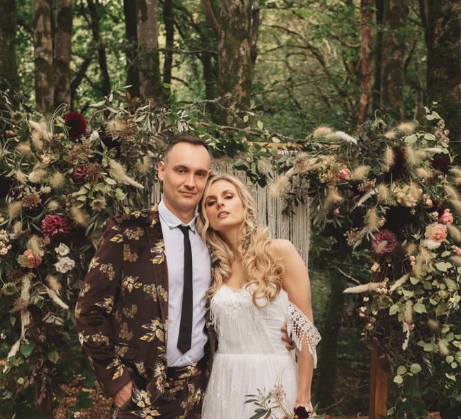 Groom in Brown Patterned Suit and Bride  Cold Shoulder Wedding Dress and Black Lace Boots