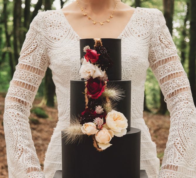 Bride in Lace Wedding Dress Holding a Black Wedding Cake