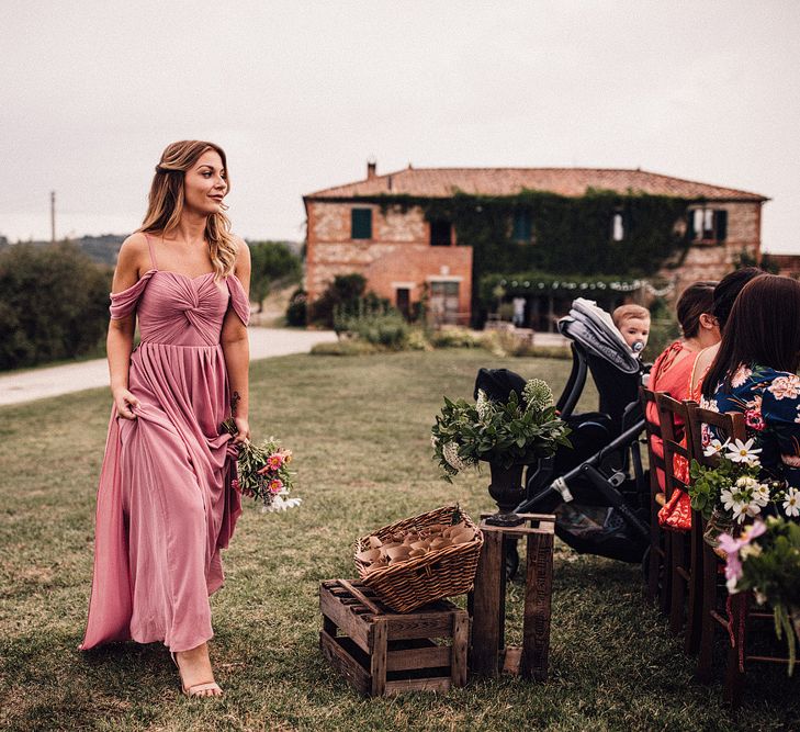 Bridesmaid in Dusky Pink ASOS Dress with Ruched Bodice and Off-Shoulder Straps | Pink, Purple and White Wildflower Bouquet Tied with Hessian and Lace | Outdoor Wedding Ceremony at Il Rigo Agriturismo, Tuscany | Rue de Seine Wedding Dress with Pronovias Overskirt, Personalised Place Setting Illustrations and Sweetheart Table | Samuel Docker Photography