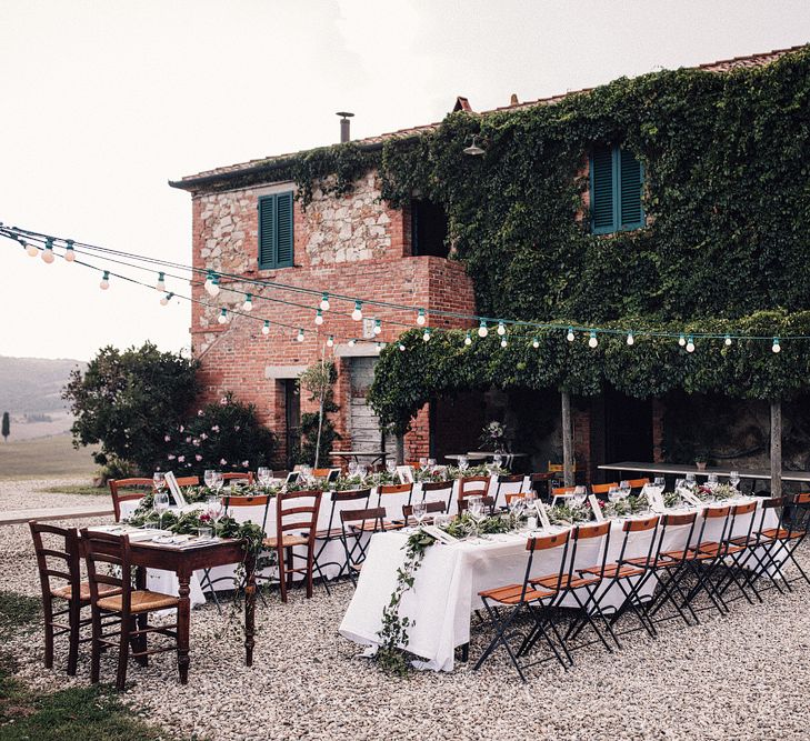 Long Banquet Tables | Sweetheart Table | Foliage Table Runners | Festoon Lights | Outdoor Wedding Reception at Il Rigo Agriturismo, Tuscany | Rue de Seine Wedding Dress with Pronovias Overskirt, Personalised Place Setting Illustrations and Sweetheart Table | Samuel Docker Photography