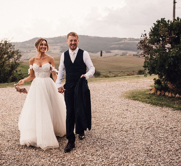 Bride in Structured Bustier Rue de Seine Fox Gown with Floral Appliqué Detail and Off The Shoulder Straps | Pronovias Chiffon Overskirt | Groom in Three-Piece Hawes &amp; Curtis Suit with Ivory Tie and Pocket Square | Rue de Seine Wedding Dress with Pronovias Overskirt, Personalised Place Setting Illustrations and Sweetheart Table | Samuel Docker Photography