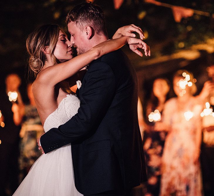 Bride in Structured Bustier Rue de Seine Fox Gown with Floral Appliqué Detail and Off The Shoulder Straps | Pronovias Chiffon Overskirt | Groom in Three-Piece Hawes &amp; Curtis Suit with Ivory Tie and Pocket Square | Sparklers | Outdoor Wedding Reception at Il Rigo Agriturismo, Tuscany | Rue de Seine Wedding Dress with Pronovias Overskirt, Personalised Place Setting Illustrations and Sweetheart Table | Samuel Docker Photography