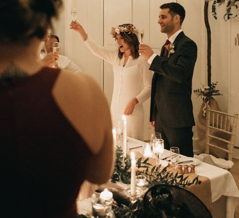 Bride and groom toast at intimate reception with boho floral decor and festoon lighting