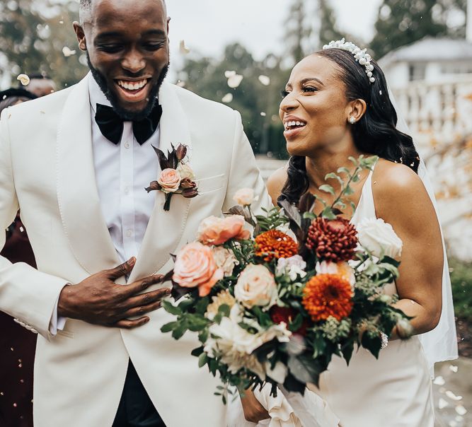 Bride and groom laughing during confetti capture at Coworth Park