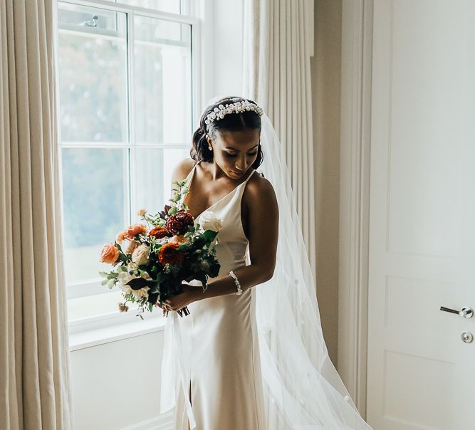 Beautiful bride in slip wedding dress holding her bouquet on the wedding morning