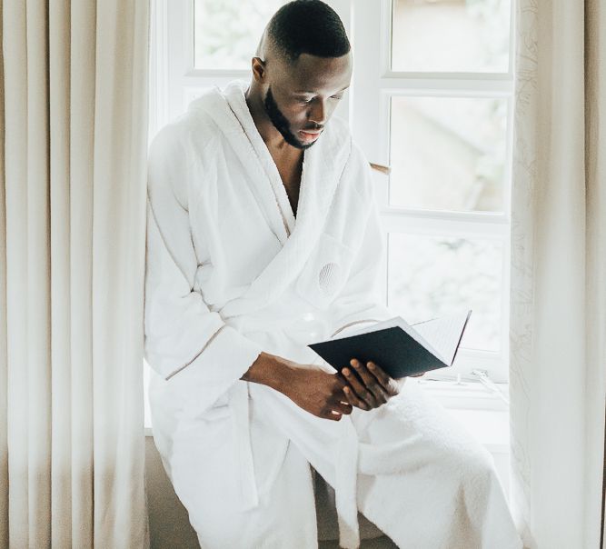 Groom in white robe on wedding morning writing his vows