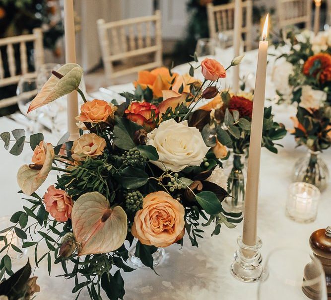 Orange wedding flowers and taper candles table decor