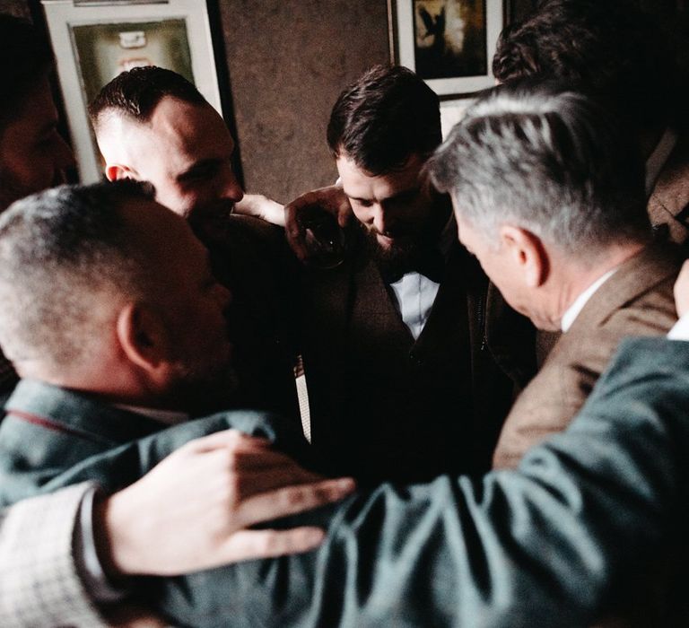 Groom wearing tweed wedding suit and his groomsmen