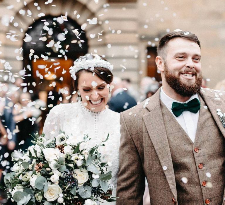 Groom wearing tweed wedding suit with green bow tie at winter celebration