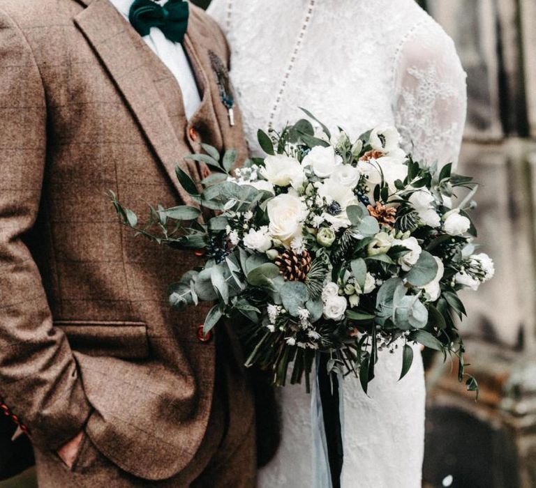 Beautiful floral bouquet with white rose foliage and tweed wedding suit