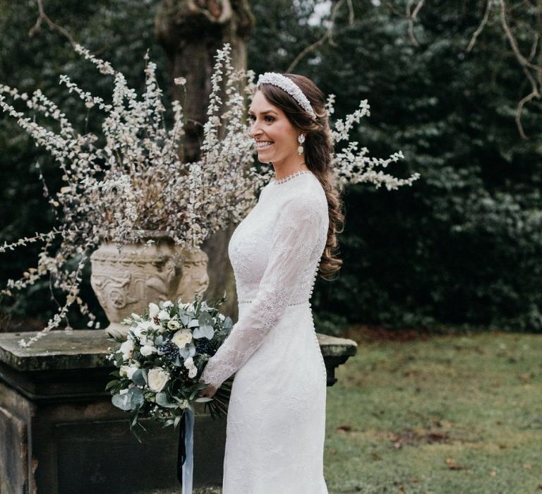 Bride wearing laced detailed dress with beautiful white bouquet