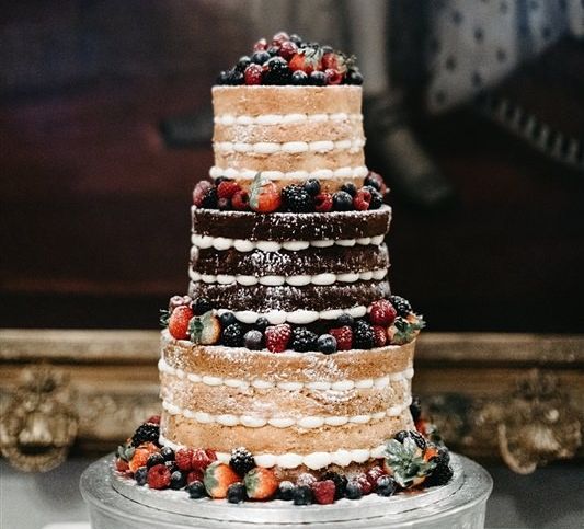 Triple tier naked cake with light frosting and berries