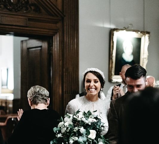 Bride and groom walk into the reception wearing tweed wedding suit